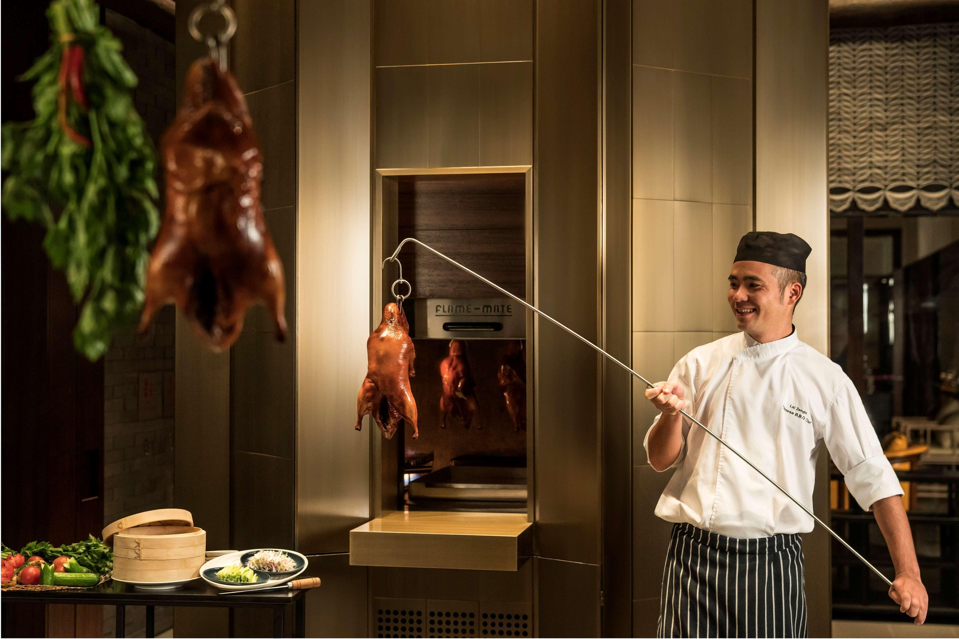 Shangri-La Kolombo Bagian luar foto Chef pulling a duck out of a hanging oven